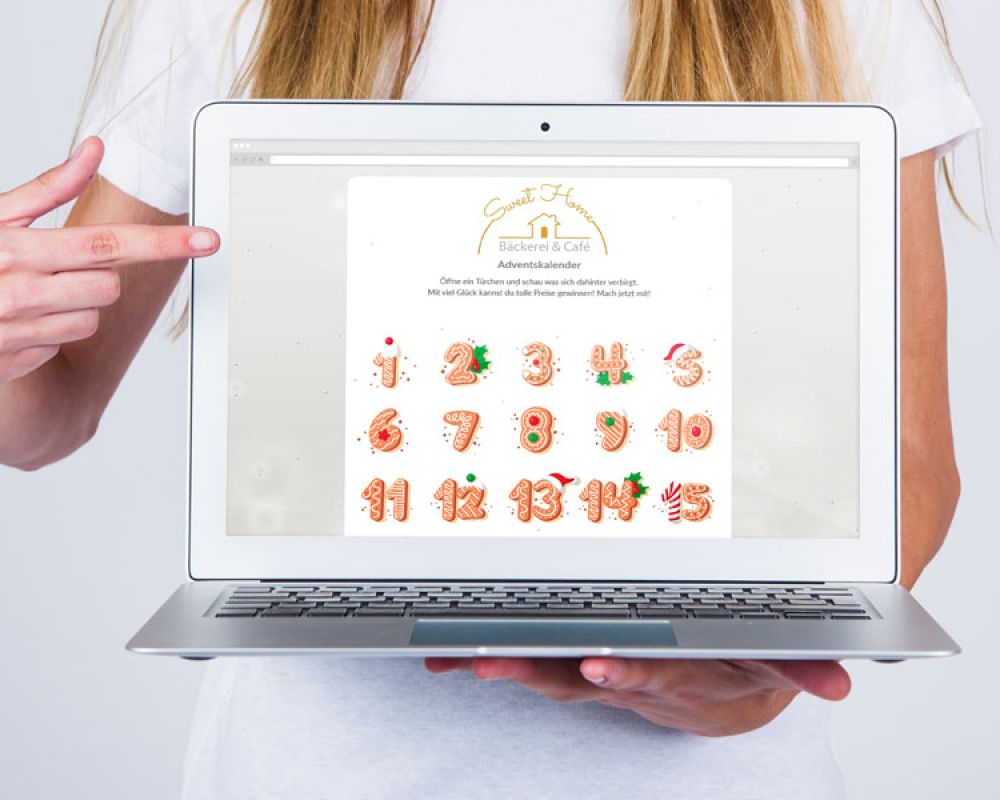 Frau zeigt auf einen Laptop-Bildschirm mit einem Adventskalender-Design von Frau zeigt auf einen Laptop-Bildschirm mit einem Adventskalender-Design von