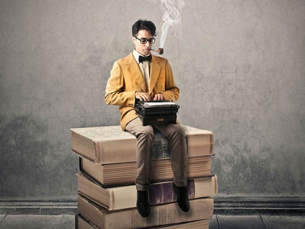 Mann sitzt auf einem Stapel Bücher und tippt auf einer Schreibmaschine, symbolisiert Ideale Webseitentexte für Google & Co.