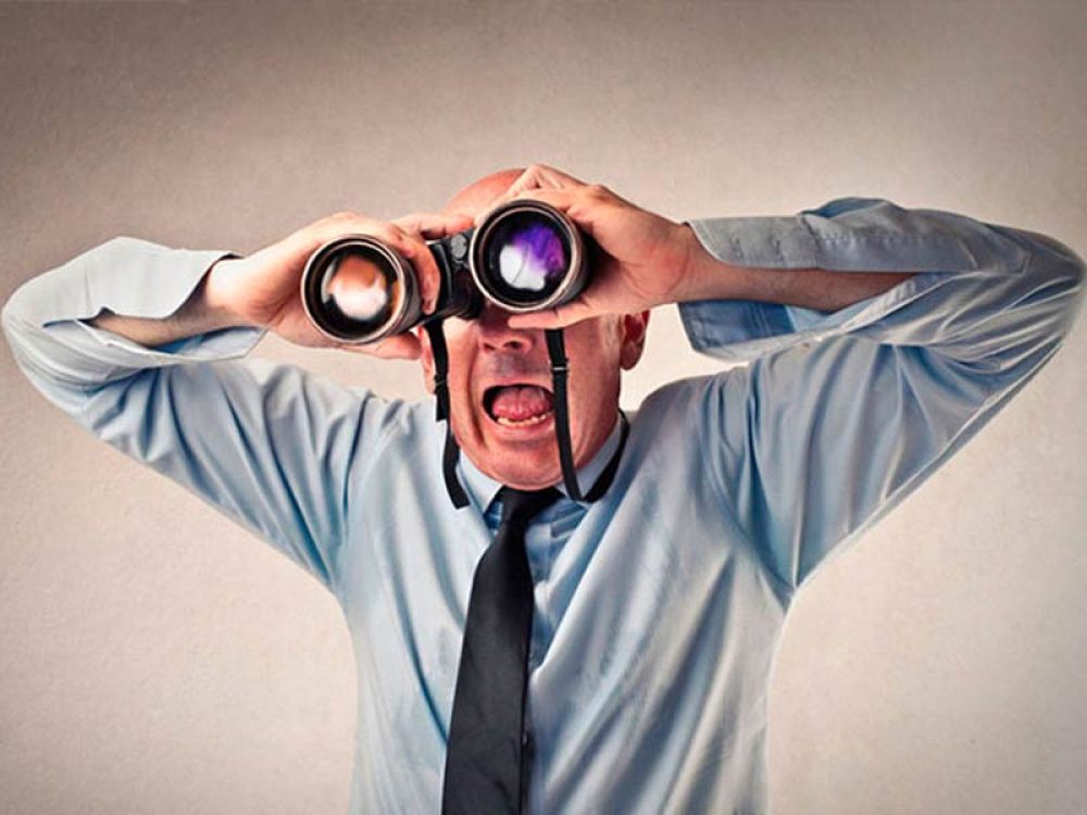Mann mit Fernglas, symbolisiert Marktbeobachtung und Wettbewerbsanalyse durch eine Marketingagentur.