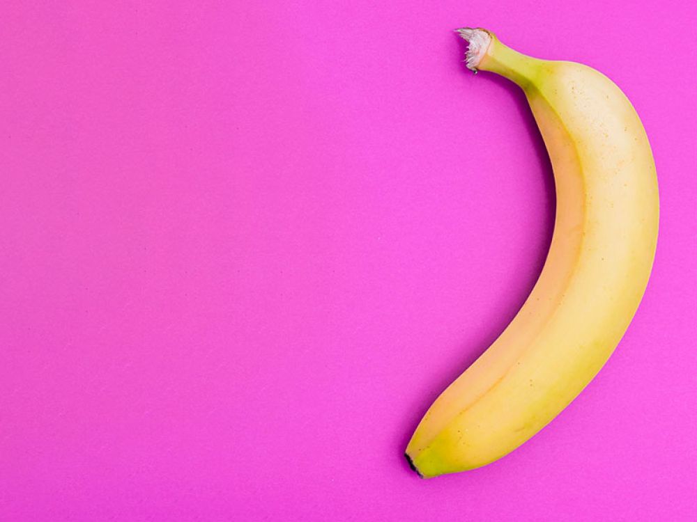 Gelbe Banane auf pinkem Hintergrund, einfache Darstellung für klaren visuellen Kontrast.